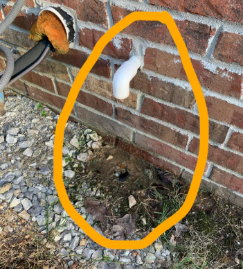 A white PVC condensate drain line cleanout pipe on the exterior wall of a home